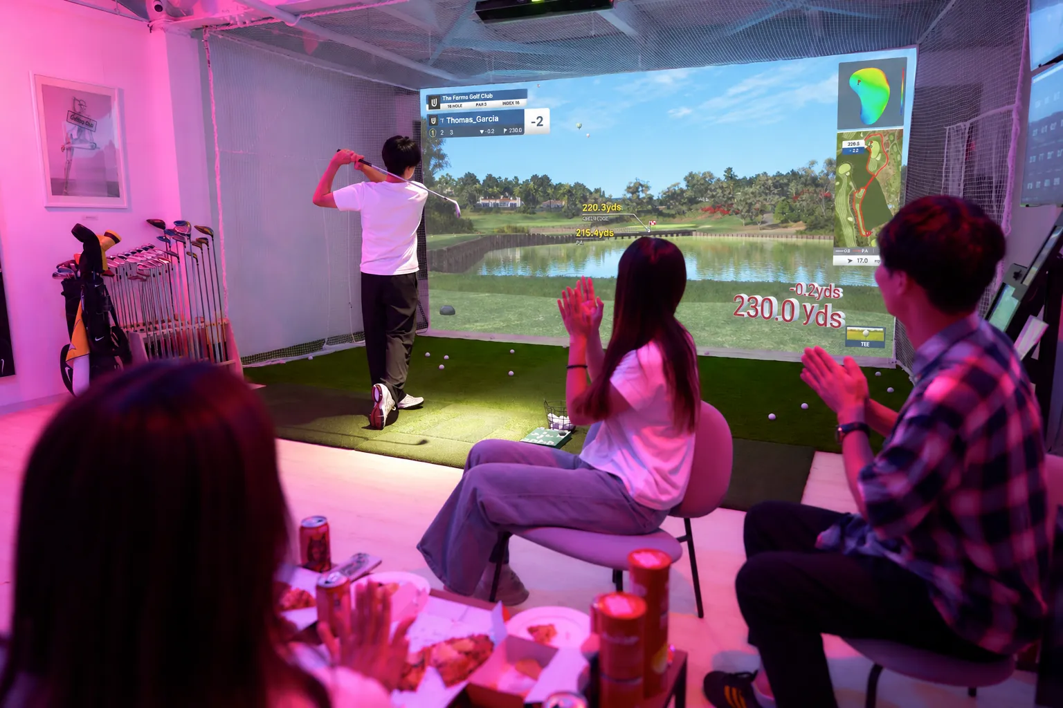 ネオンの打席で GAMEDAY をプレーするゴルファーと、歓声を上げる仲間（施設写真をもとにした合成イメージ）